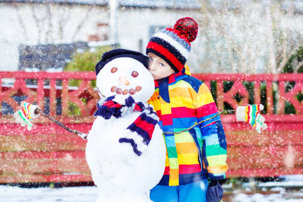 istock Funny kid boy making a snowman in winter 873873074
