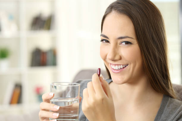 istock Happy woman looking at camera holding a pill 873873690