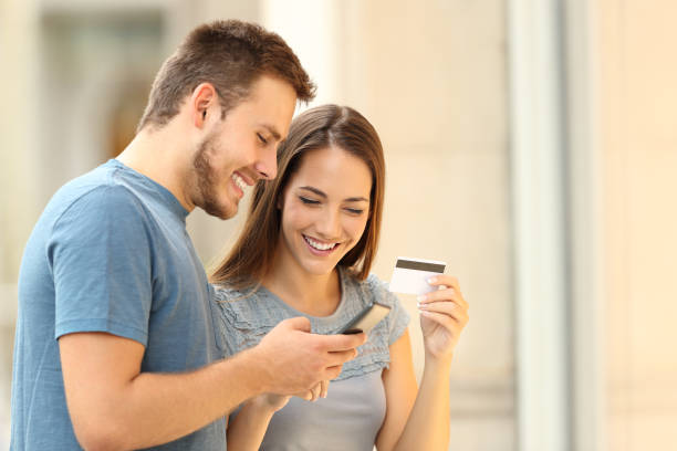 couple paying on line with credirt card on the street - shopping e commerce internet credit card imagens e fotografias de stock