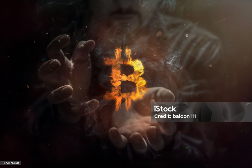 Burning symbol of bitcoin with man in the background. Conception of risk management in money trading at currency market Bitcoin Stock Photo