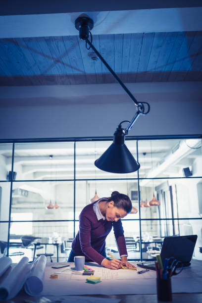 Working Late. Young woman, architect working late in office Young woman architect (designer), working on a project. Modern architectural studio architectural stele stock pictures, royalty-free photos & images