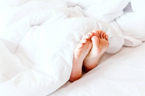 istock Young woman's bare feet on white blanket 873886692