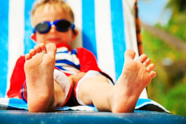 istock little boy relax on tropical beach, focus on feet 873888032