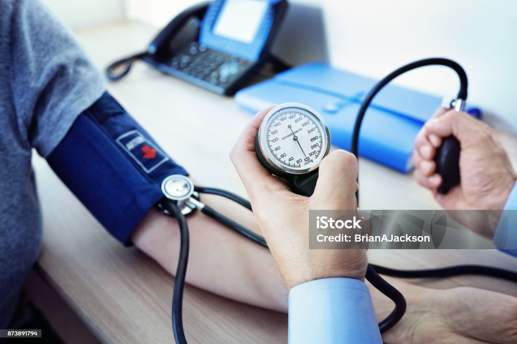 Doctor measuring blood pressure of patient Doctor checking the blood pressure of a patient Blood Pressure Gauge Stock Photo