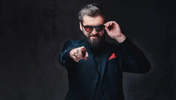 Photo of A man dressed in a suit and sunglasses.