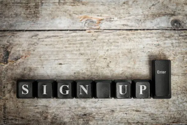 Photo of keys on a wooden table with the words sign up ,conceptual