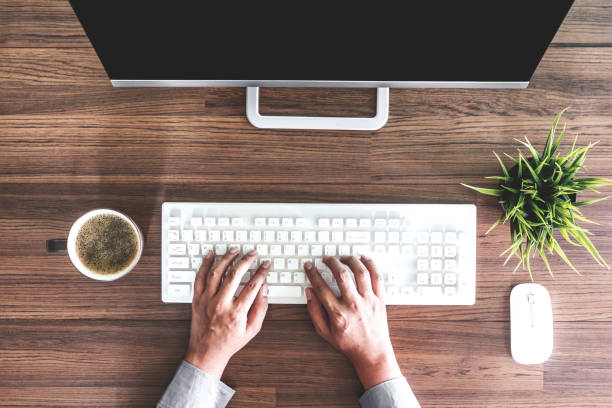 istock Businessman hand uses computer with working place on wooden table 873898388