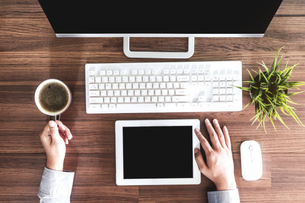 istock Businessman hand uses a tablet and computer with working place on wooden table 873898390