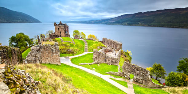 暗い雲空とアーカート城 - urquhart castle ストックフォトと画像