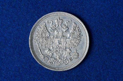silver retro coin lies on a blue background of a piece of woolen fabric