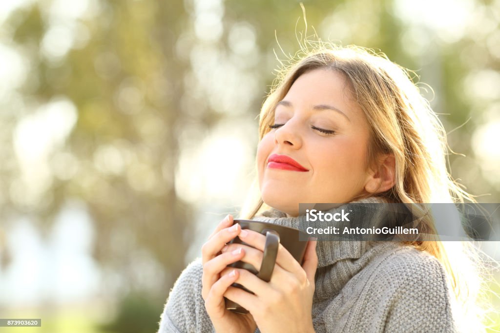Relaxed girl breathing outdoors in winter Portrait of a relaxed girl wearing jersey holding a cup of coffee and breathing outdoors in a park in winter Women Stock Photo