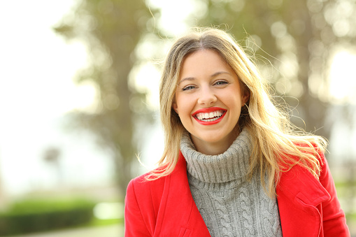 Portrait of a happy woman laughing wearing red jacket and looking at camera in winter
