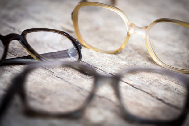 three old nerdy hornrims or eye glasses on wooden table
