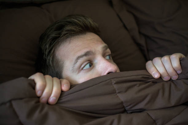 istock Caucasian young man hiding in bed under the blanket at home. 873908724