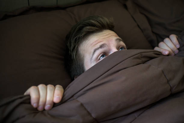 istock Caucasian young man hiding in bed under the blanket at home. 873908832
