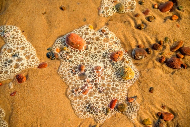 Sandy beach with foam of the surf and pebbles