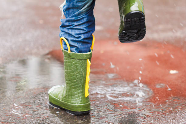 istock child with rain boots jumps into a puddle 873917906