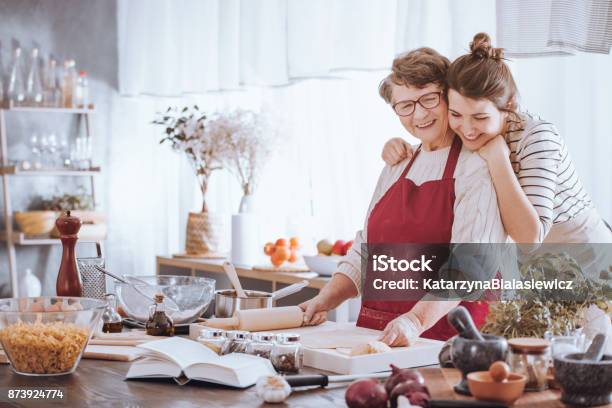 Granddaughter Hugging Grandmother In The Kitchen Stock Photo - Download Image Now - Christmas, Cooking, Family