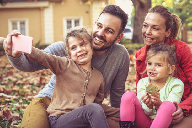 padre ayuda a la niña para tomar un retrato del uno mismo de toda familia. - two parent family technology mobility men fotografías e imágenes de stock