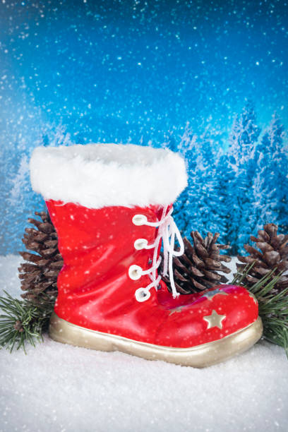 istock Christmas decoration with red boot and pines on a background with white snow and blue pine tree landscape 873927490