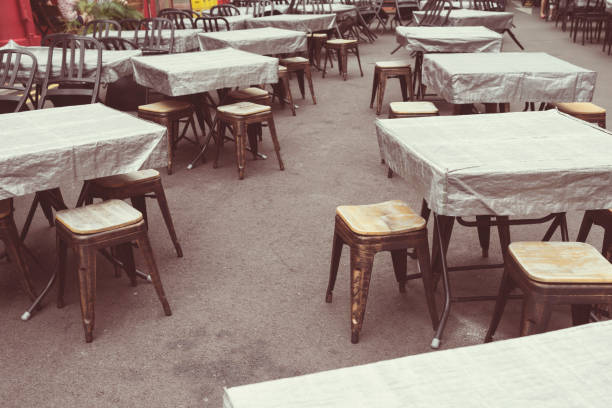 Empty  terrace with tables and chairs in wood and metal at coffee and resteurant beside sidewalk in center city. Environment city life during confinement due to corona virus or covid-19  Background business dramatic scene conept.