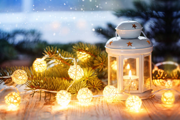 istock Christmas decoration with white candle lantern, fir tree branches and luminous garland. 873932290