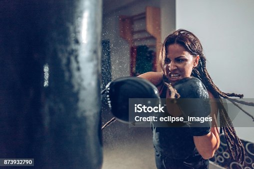 istock Female kickboxer training with a punching bag 873932790