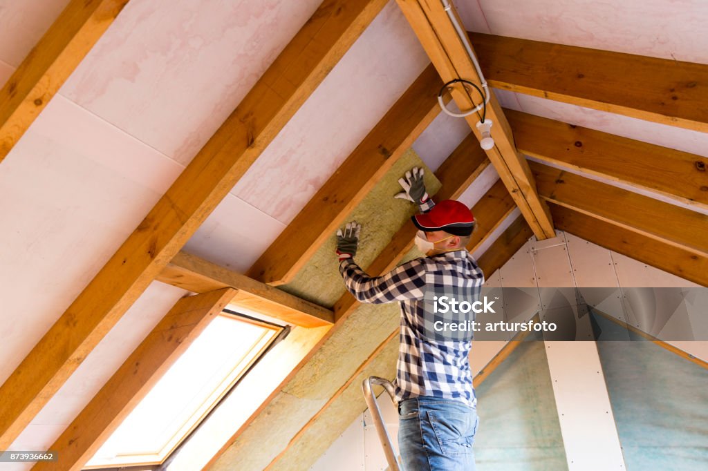 Man installing thermal roof insulation layer - using mineral wool panels. Attic renovation and insulation concept Insulation Stock Photo