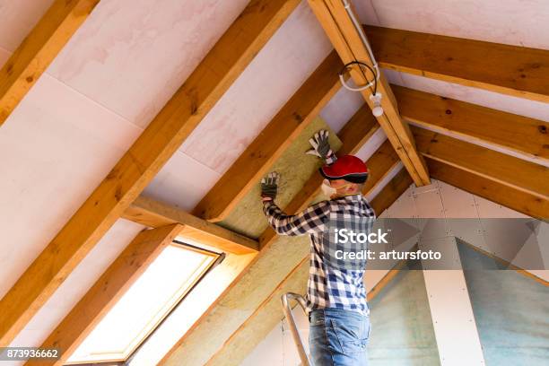 Man Installing Thermal Roof Insulation Layer Using Mineral Wool Panels Attic Renovation And Insulation Concept Stock Photo - Download Image Now