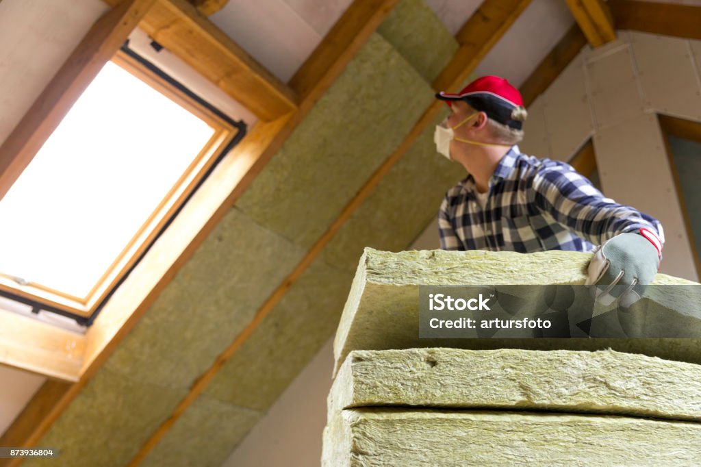 Man installing thermal roof insulation layer - using mineral wool panels. Attic renovation and insulation concept Insulation Stock Photo