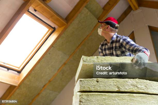 Man Installing Thermal Roof Insulation Layer Using Mineral Wool Panels Attic Renovation And Insulation Concept Stock Photo - Download Image Now