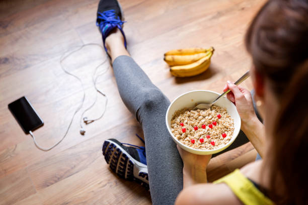 young girl eating a oatmeal with berries after a workout . fitness and healthy lifestyle concept. - eating eat silverware horizontal imagens e fotografias de stock