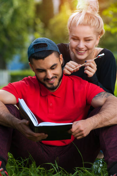 istock young romantic couple reading book in park 873945578