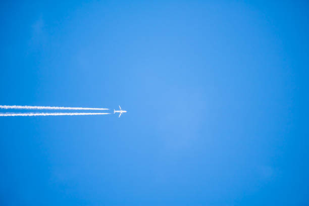 istock plane isolated flying high above in blue sky, travel concept 873946234