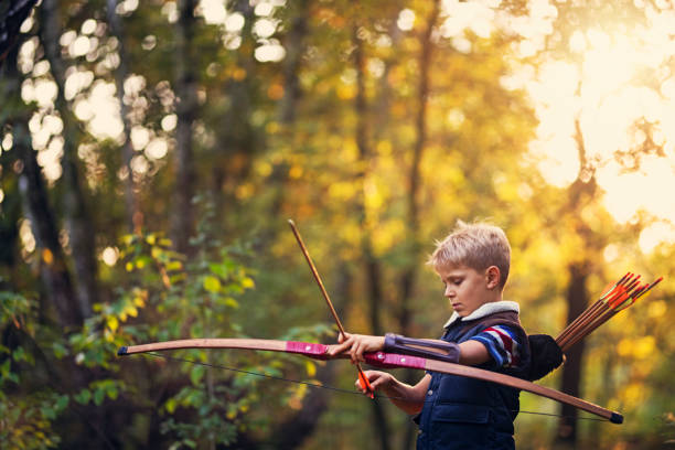 istock Little boy playing with bow in forest 873946602