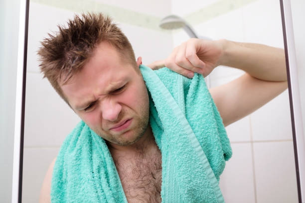 Young man cleaning his ear while taking a shower and standing under flowing water stock photo