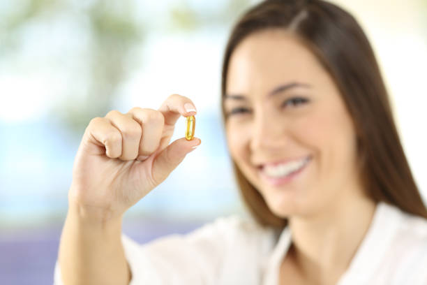 istock Happy woman showing an omega 3 pill 873953178