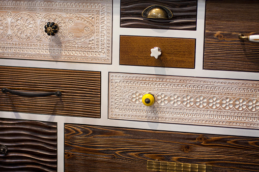 Close-up on decorative ornate wooden drawers all different with different handles.