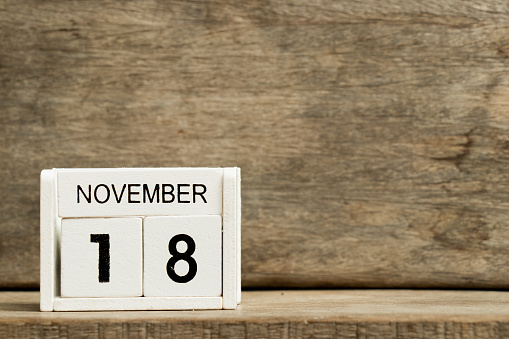 White block calendar present date 18 and month November on wood background