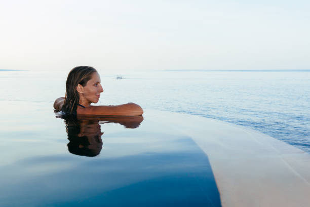 istock Woman at infinity swimming pool with sea view 873961034