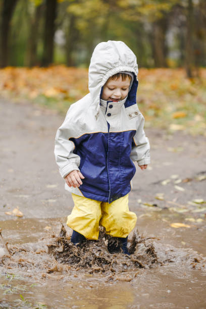 istock Happy child jumping on puddles in rubber boots 873965432