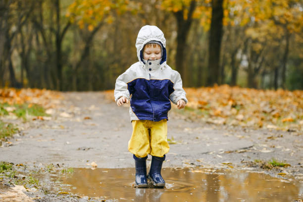 istock Happy child jumping on puddles in rubber boots 873966510