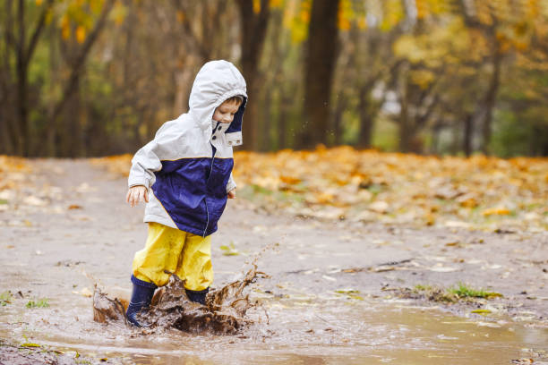 istock Happy child jumping on puddles in rubber boots 873971536