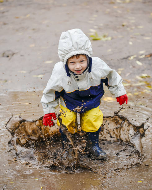 istock Happy child jumping on puddles in rubber boots 873972204