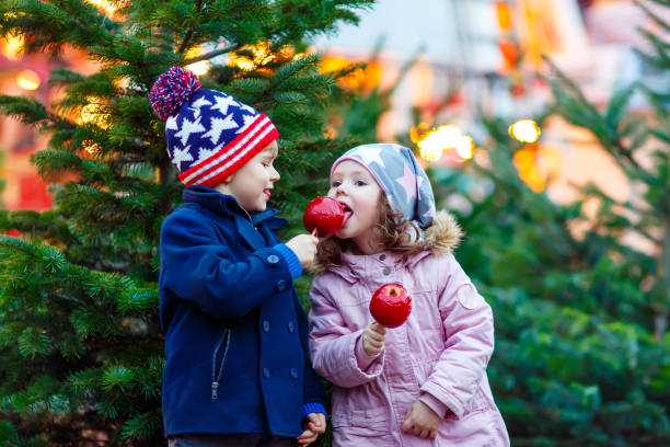 istock Two little kids eating crystalized apple on Christmas market 873972588