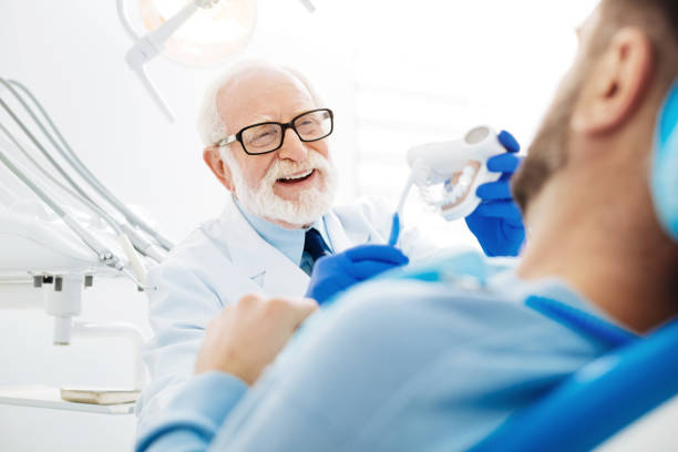 istock Pleased dentist holding false teeth with tooth brush in hand 873991070