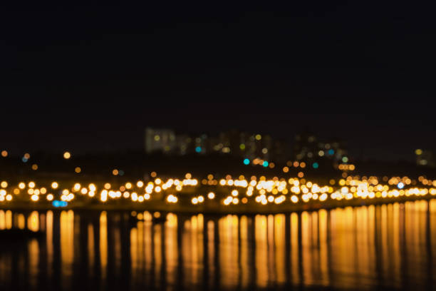 città illuminata sfocata astratta con riflessione nel lago. sfondo notturno sfocato con bokeh - blurred motion circle reflection illuminated foto e immagini stock