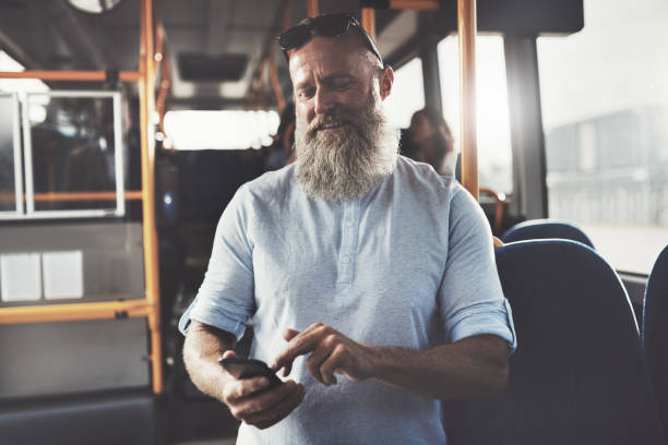 istock Smiling man with a beard sending texts on the bus 874011774