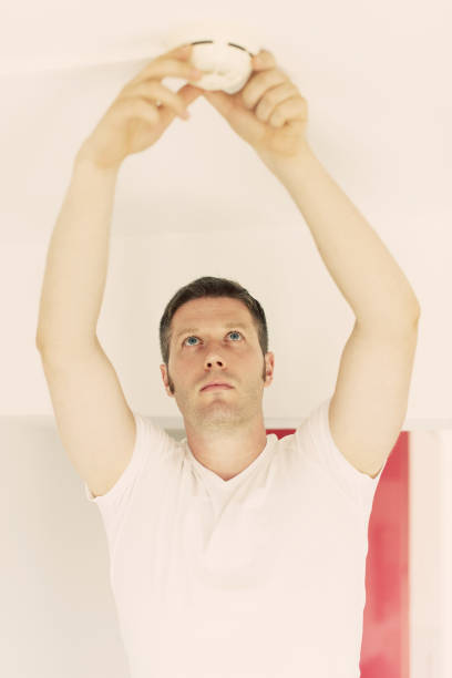 istock Male technician installing smoke detector at home. 874012886