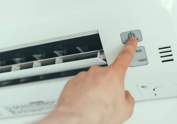 istock Male hand turns on air-conditioning system. 874012912